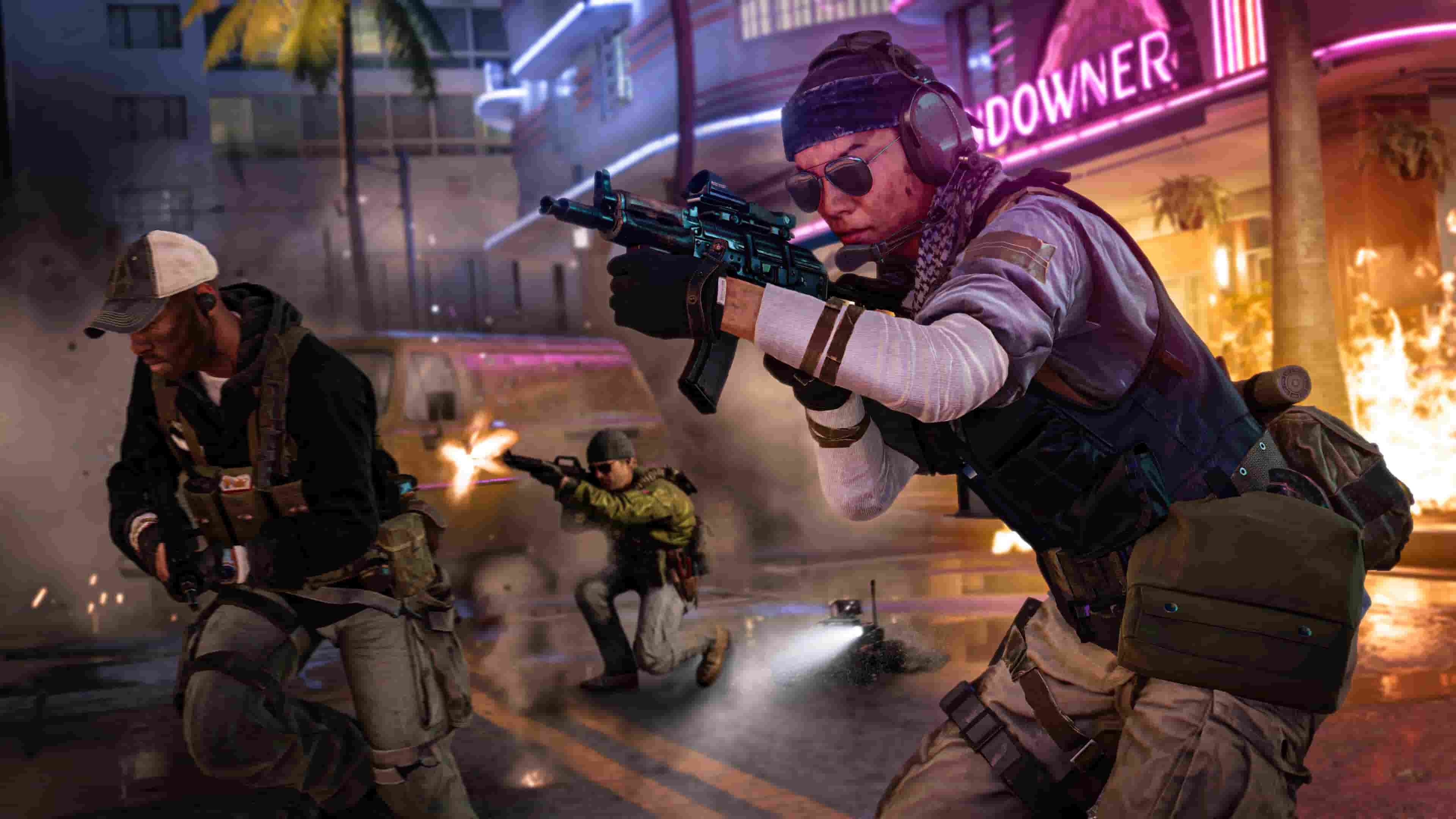 A soldier aiming down his weapon sight, with teammates running behind him in front of a bar with a neon sign. 