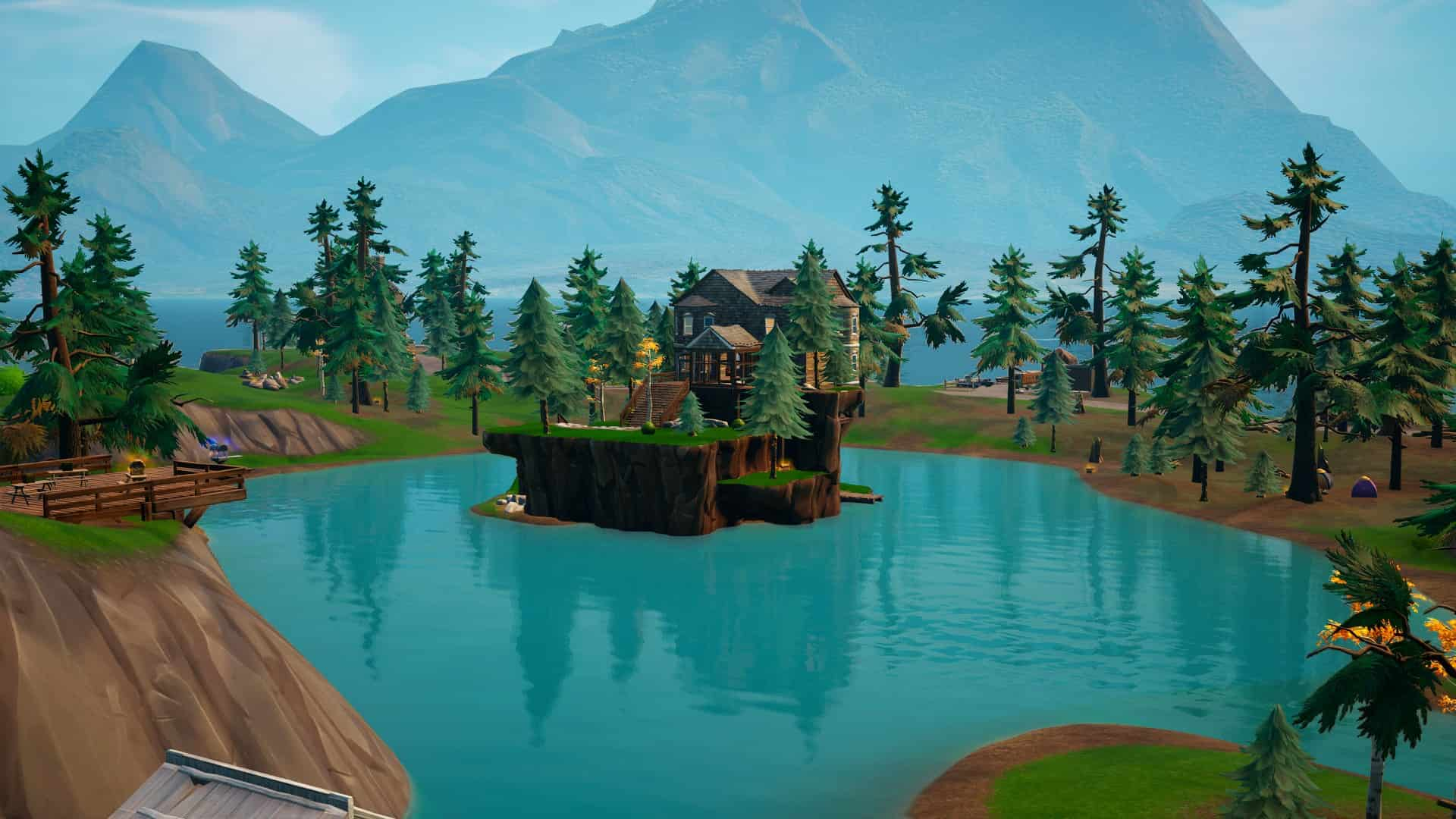 A house sitting on a small island in the middle of a blue lake, with trees around it. 