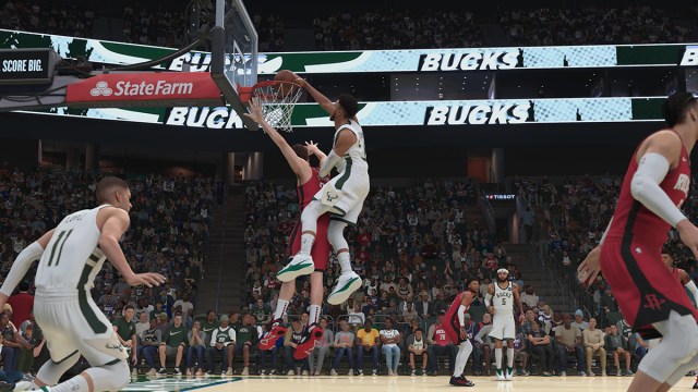 Giannis Antetokounmpo performs a dunk over a defender.