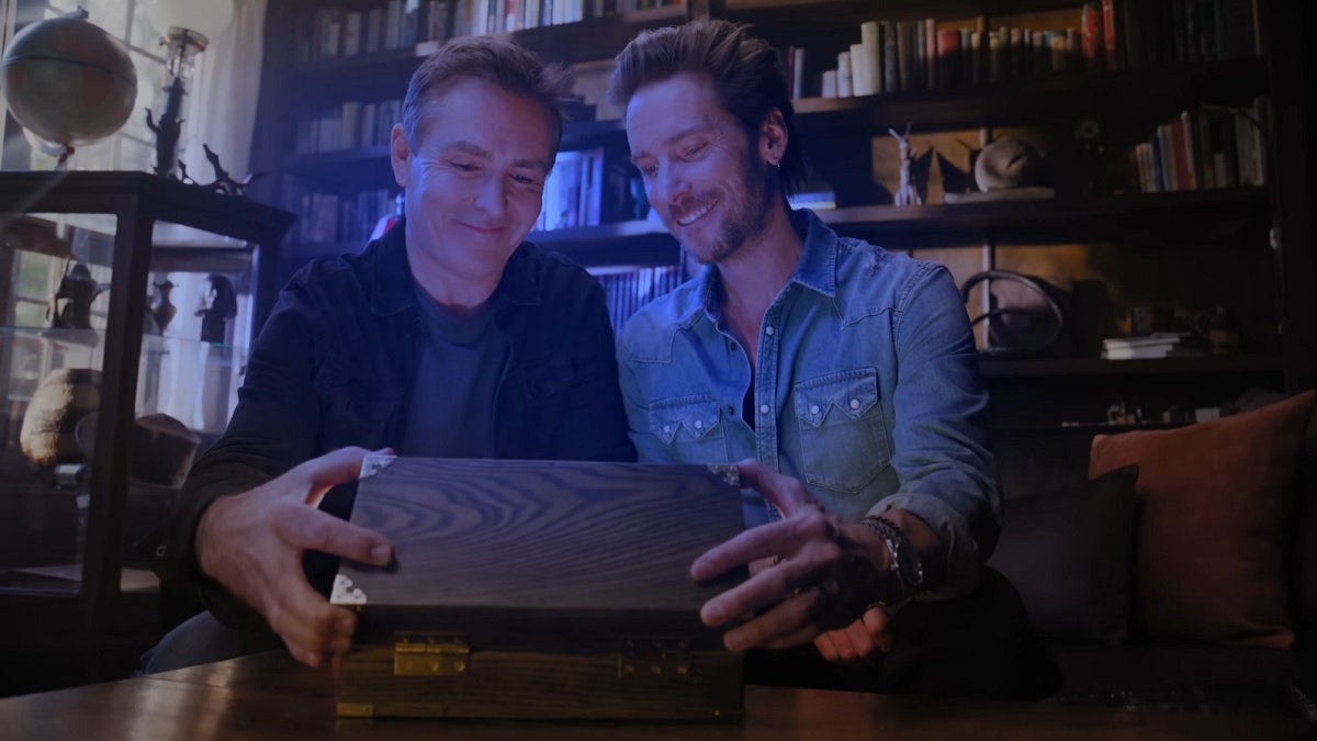 Indiana Jones and the Great Circle: actors Nolan North and Troy Baker open a small box, which reveals a bright blue light.
