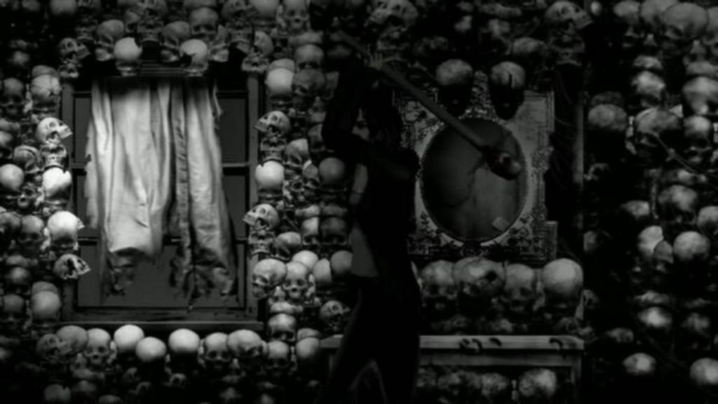 Susan swinging an axe in front of a wall of skulls