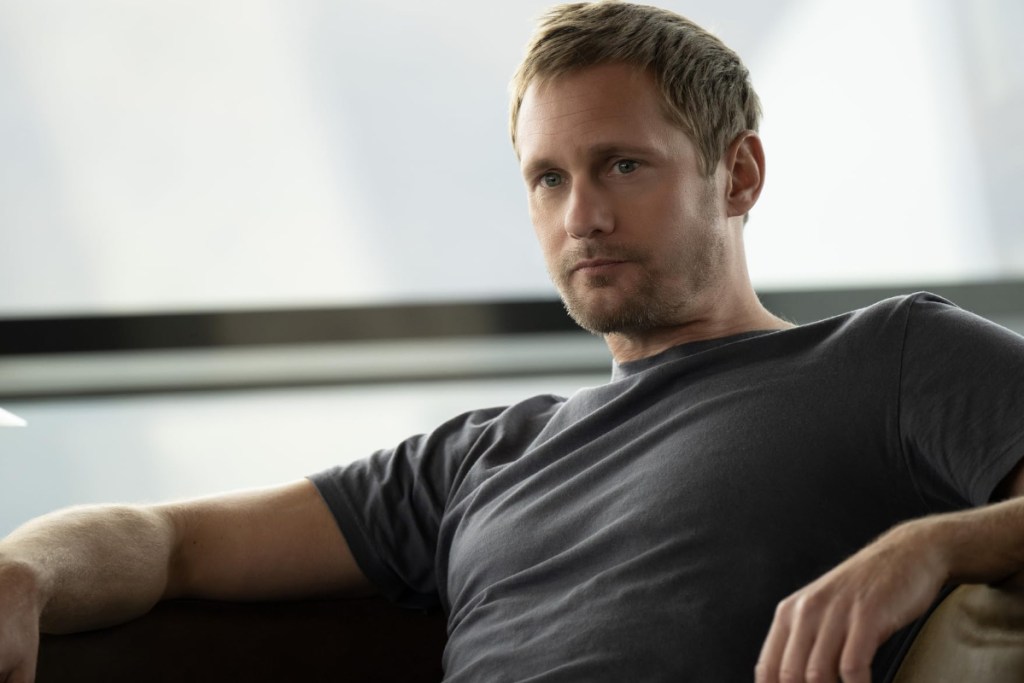 Alexander Skarsgaard actor sitting in a chair and looking to the side of the camera.