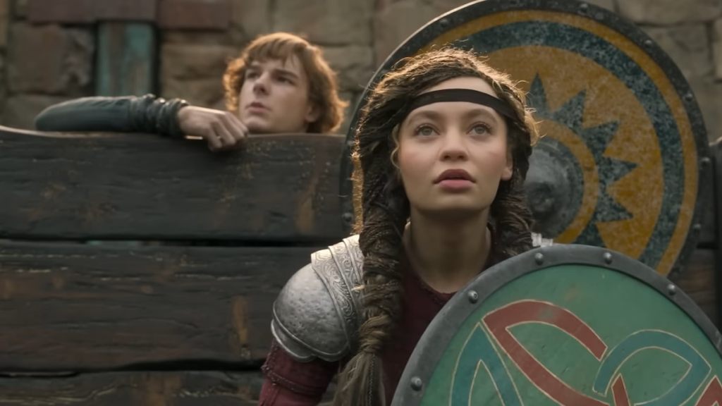 Hiccup hidding behind a wooden board and astrid standing in front of it with a shield in how to train your dragon