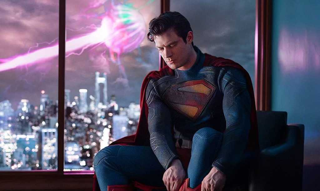 Superman lacing his boots as an alien monster blasts behind him