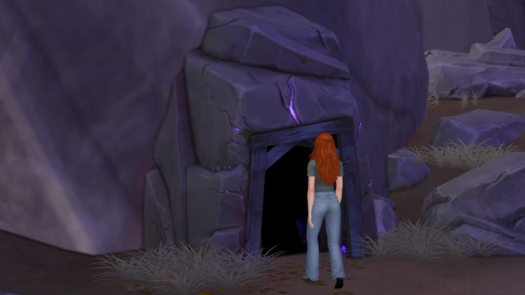 A Sim with orange hair walking into a rocky cave in the sims 4