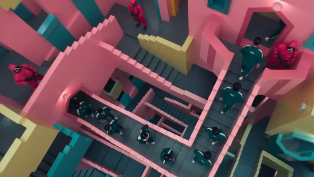 Squid Game players in green tracksuits walking up colorful stairs