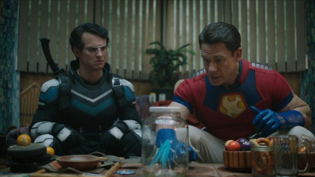 Vigilante and Peacemaker looking at a butterfly in a jar